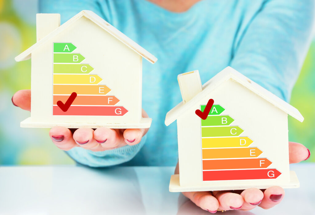 Twee houten huisjes met energielabels, links met een rood vinkje op label G en rechts met een groen vinkje op label A, als illustratie van energiezuinigheid bij woningen.