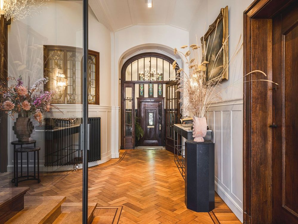 Elegante entree van Heemraadssingel 109 met originele houten elementen, glas-in-loodramen en een stijlvolle, warme uitstraling.