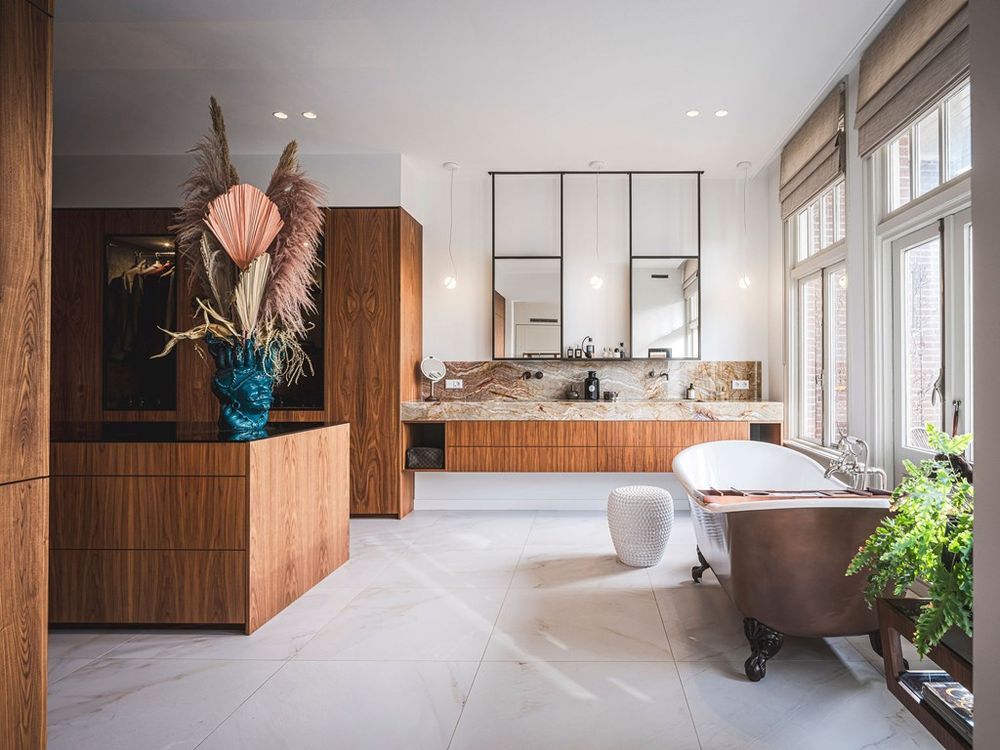 Luxe badkamer van de master suite in Heemraadssingel 109, met een vrijstaand koperen bad, onyx marmeren wastafel en maatwerk kastinterieur van Amerikaans notenhout.