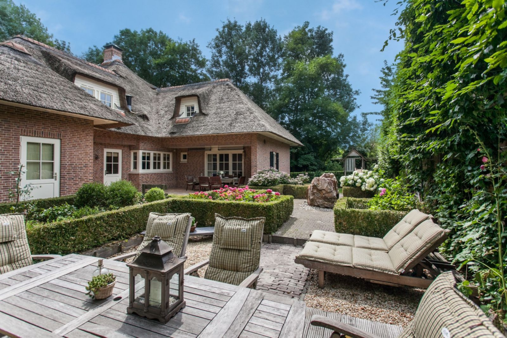 Ruime tuin van een luxe villa in villawijk Bosweide, Den Haag, met overdekt terras, stijlvolle beplanting en comfortabele zitplekken.