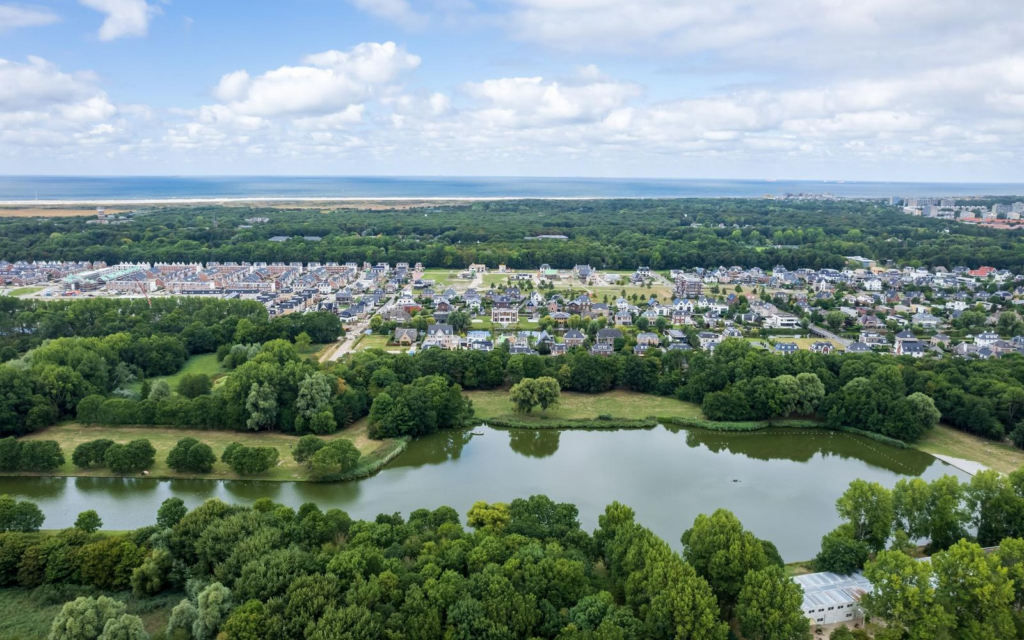 Luchtfoto van de villawijk Vroondaal in Den Haag, met zicht op het Grand Canal en de omliggende natuur.