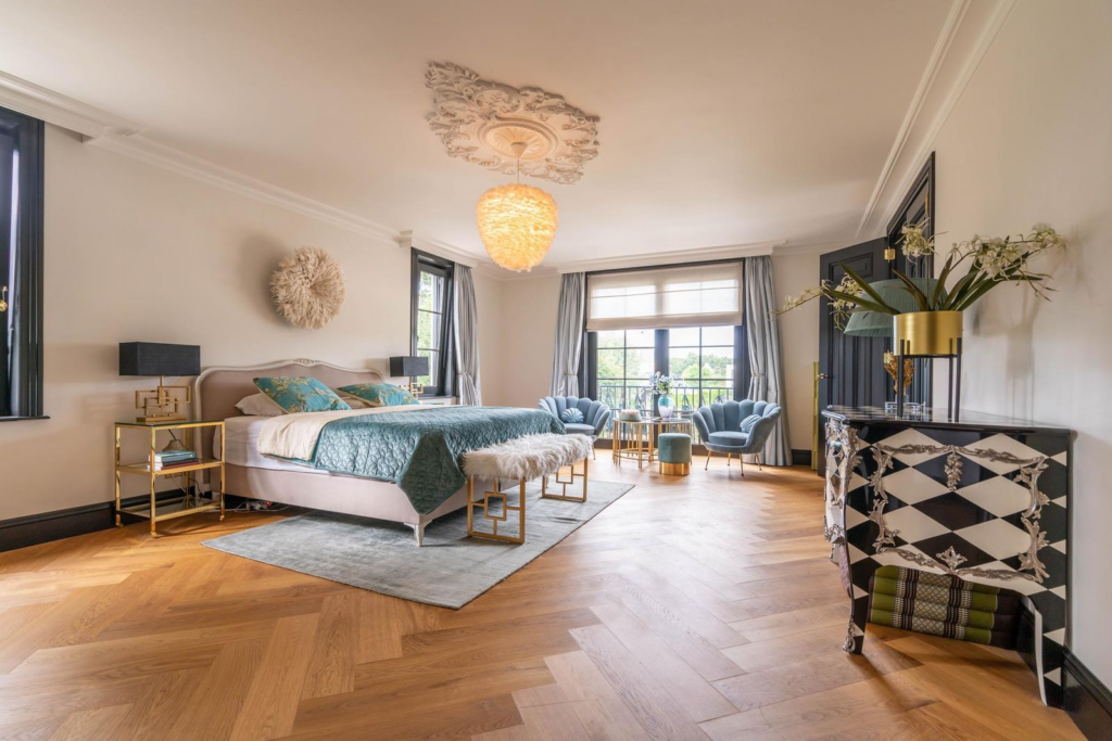 Ruime en elegante master bedroom in luxe villa met grote ramen, visgraat parketvloer en stijlvolle inrichting.