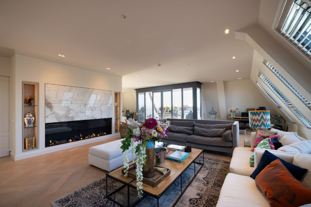 Ruime en luxe living in het penthouse van Villa Jarpa, met een moderne haard, grote raampartijen en stijlvolle inrichting.