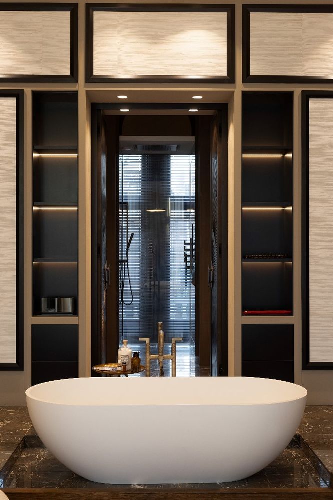 Een luxe badkamer met een prachtig vrijstaand bad als eyecatcher. De combinatie van warme tinten, strakke lijnen en verfijnde verlichting creëert een serene en elegante sfeer, perfect voor ontspanning en luxe.