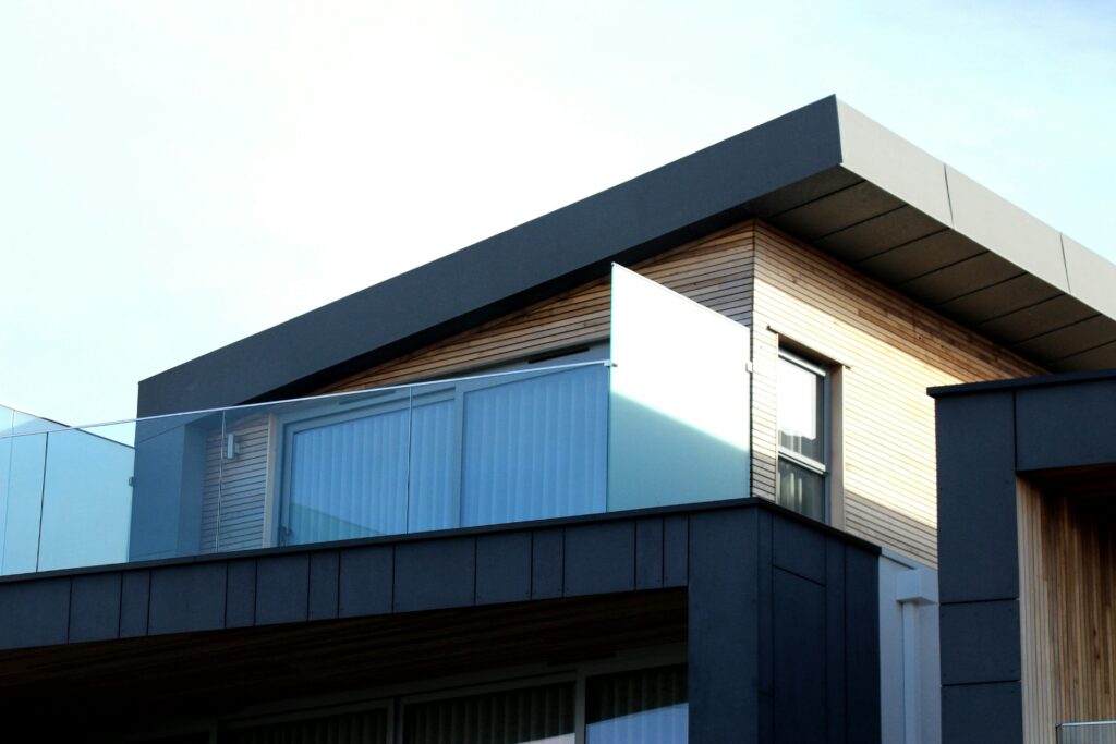 Modern huis met houten gevelbekleding en glazen balustrades, waarbij bitumen gebruikt is voor een duurzaam en waterdicht dak.