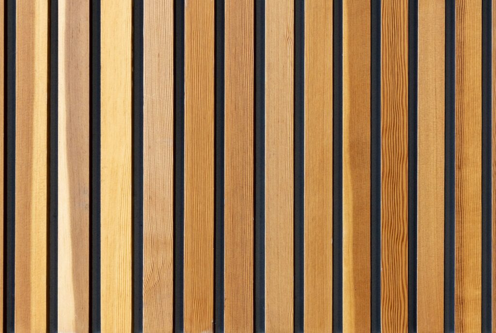 Close-up van houten akoestische wandpanelen met natuurlijke houttinten en zwarte tussenruimtes, ideaal voor een geluiddempende en stijlvolle interieurtoepassing.