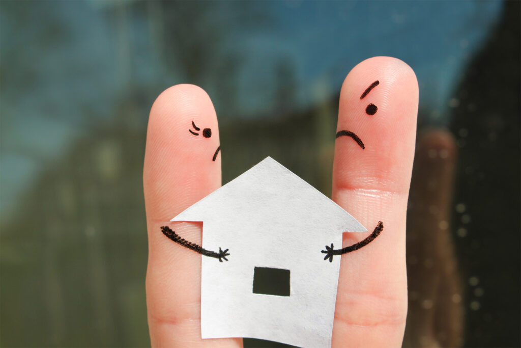 Twee vingers met boze gezichten en een papieren huisje ertussen als metafoor voor burenruzies en spanningen in de buurt