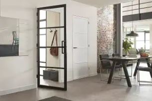 Stalen binnendeur met glas in een moderne woning, die een entree scheidt van een eetkamer met industriële accenten en veel lichtinval.
