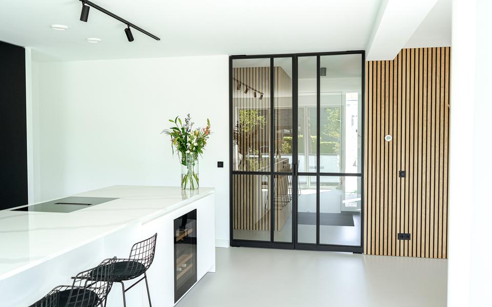Moderne keuken met een stalen binnendeur voorzien van glas, gecombineerd met houten wandbekleding en een licht interieurontwerp