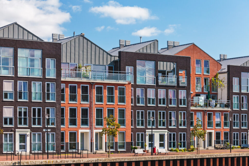 Moderne appartementen aan het water met een combinatie van rode en donkere bakstenen gevels, grote ramen en balkons. Een representatief beeld van de Nederlandse woningmarkt in 202