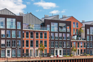 Moderne appartementen aan het water met een combinatie van rode en donkere bakstenen gevels, grote ramen en balkons. Een representatief beeld van de Nederlandse woningmarkt in 202