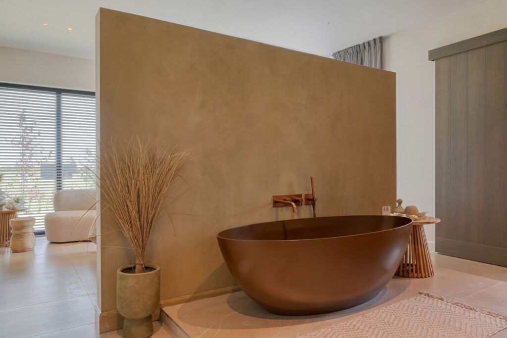 Elegante badkamer met vrijstaand bronzen ligbad, dubbele wastafel en inloop-regendouche in een luxe woning.