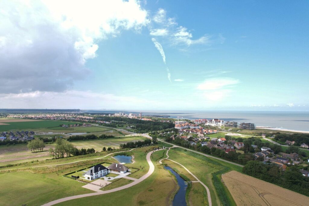 Luchtfoto van een luxe landhuis op Landgoed Nooren in Cadzand, omringd door groen en waterpartijen, met uitzicht op de kust en duinen.