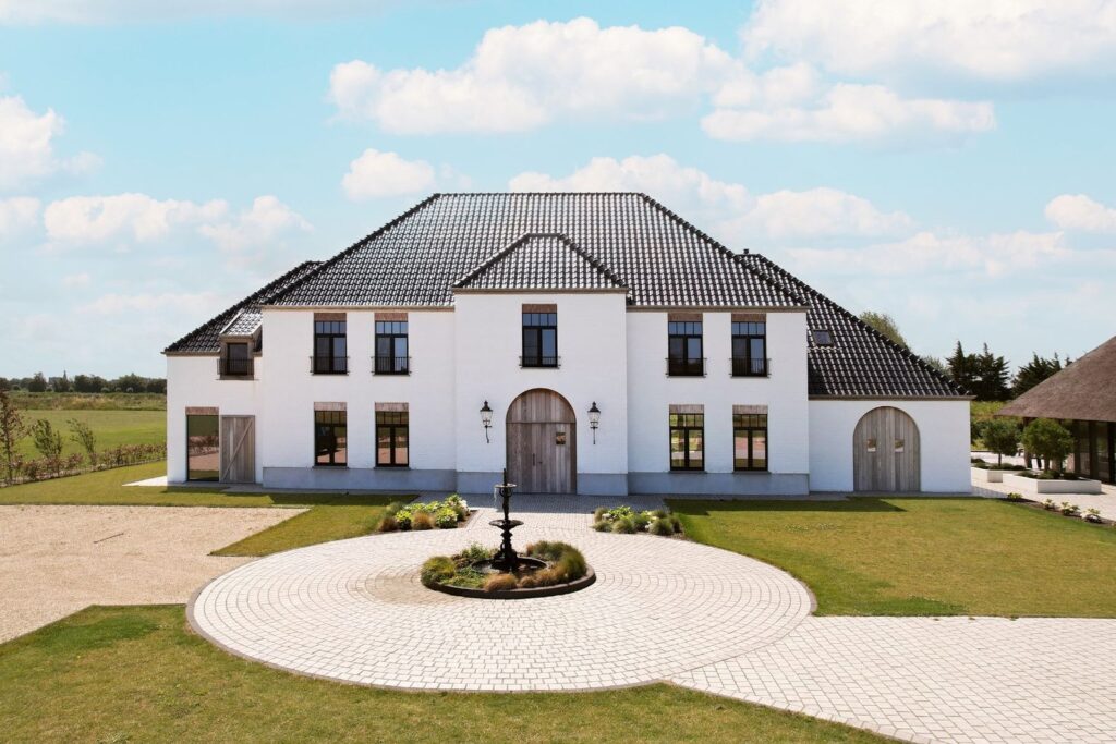 Statig wit landhuis op Landgoed Nooren in Cadzand, omgeven door groen en met een elegante oprijlaan