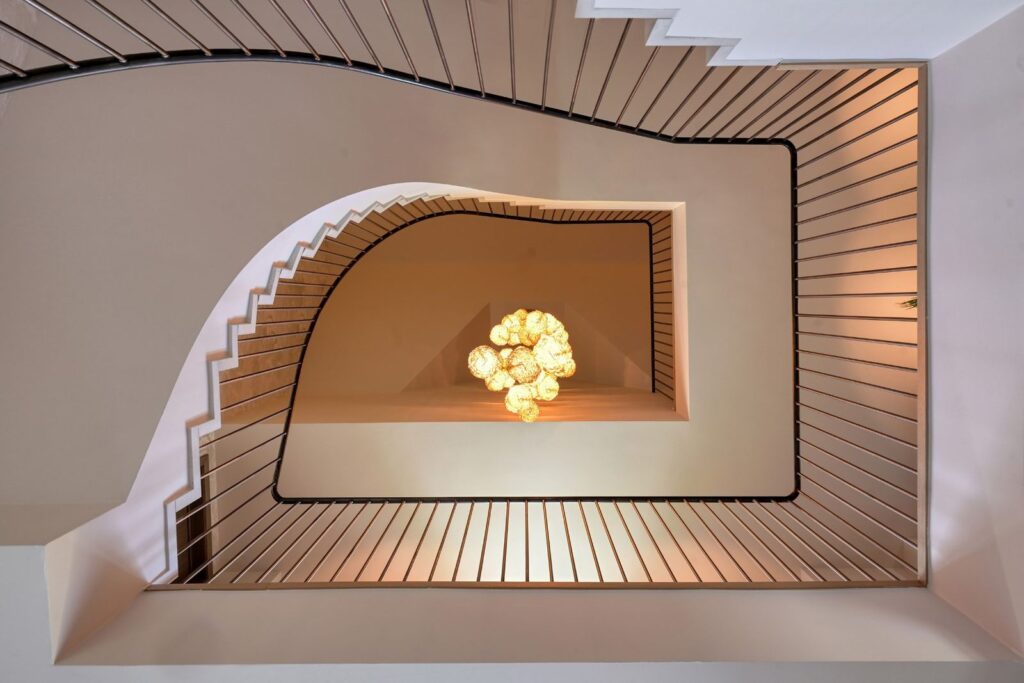 Indrukwekkend bovenaanzicht van een luxe trappenhuis met strakke lijnen en een designlamp als blikvanger.