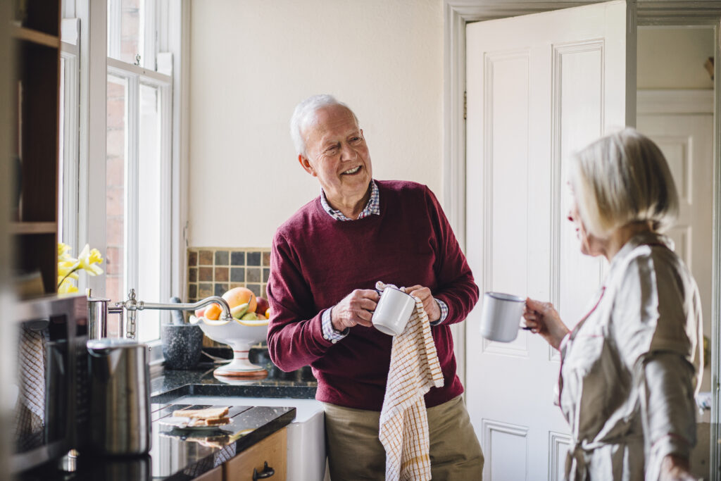 Oudere man en vrouw drinken samen koffie in de keuken – ontspannen en vertrouwd