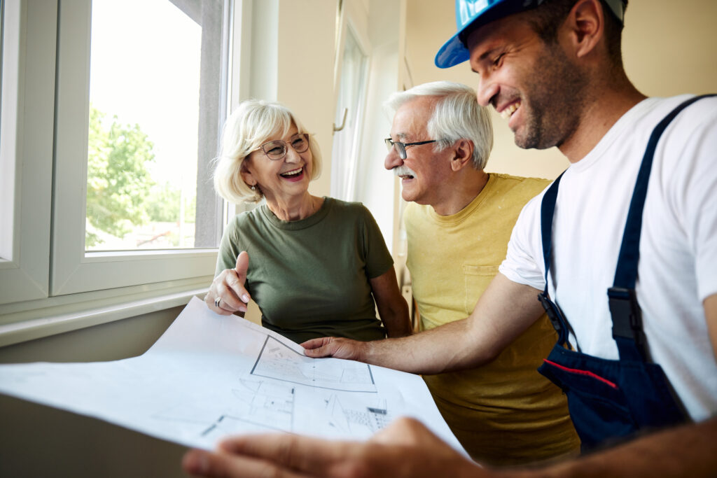 Oudere man en vrouw bekijken bouwtekening samen met aannemer voor een toekomstbestendige woning