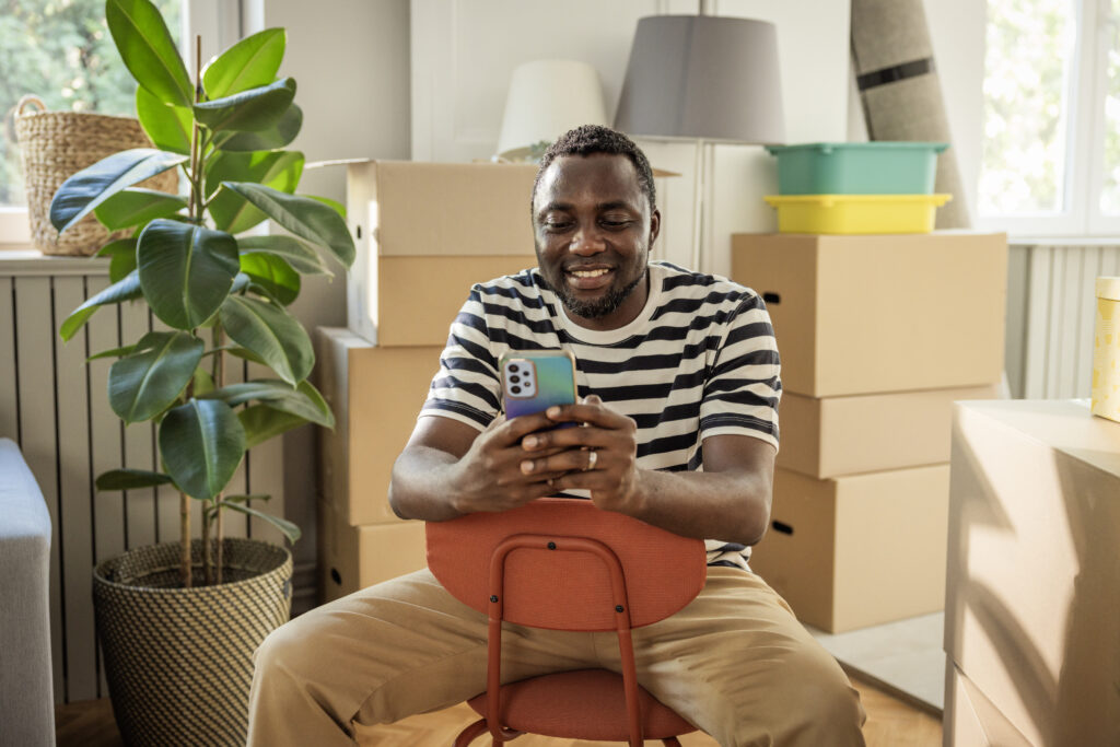 Man regelt zijn verhuizing via smartphone tussen verhuisdozen in zijn nieuwe woning