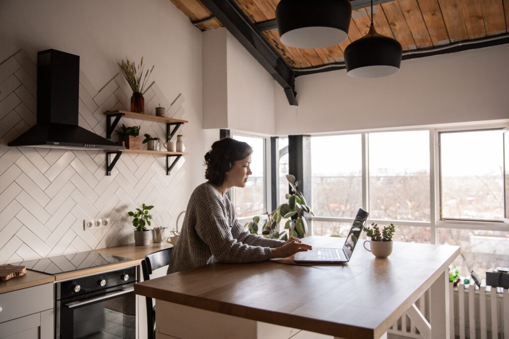 Vrouw werkt geconcentreerd aan het keukeneiland met laptop en koptelefoon