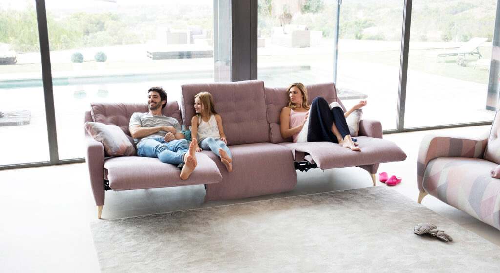 Gezin zit ontspannen op een roze relaxbank van Fama met verstelbare voetensteunen.