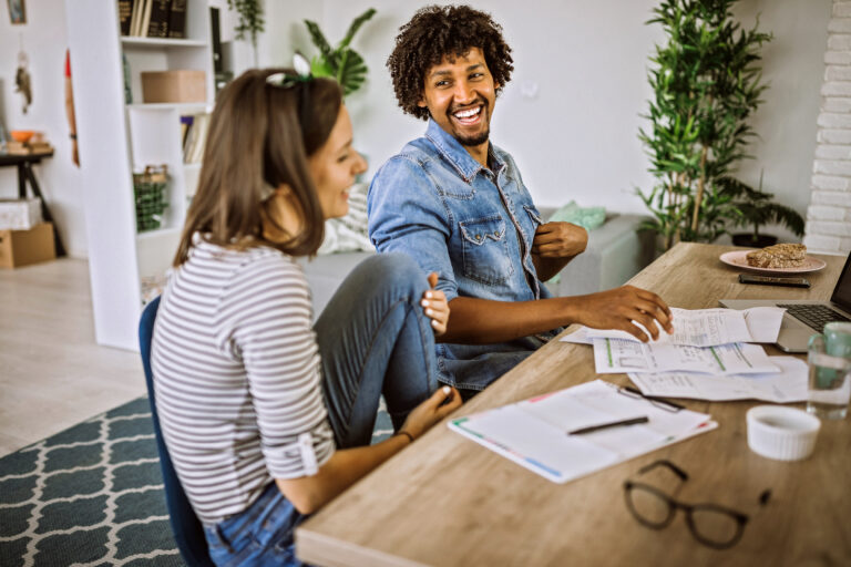 Jong stel zit samen aan tafel en regelt praktische zaken voor hun woning