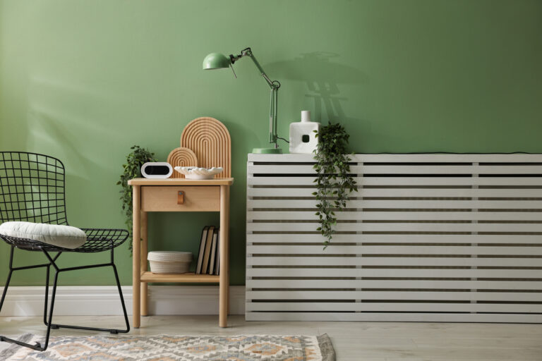 Moderne woonkamer met groene muur en strakke radiatorombouw die naadloos opgaat in het interieur.