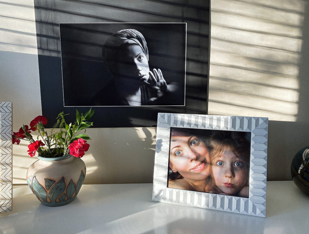 Ingelijste foto’s en persoonlijke objecten op een plank in een bewoonde woonkamer