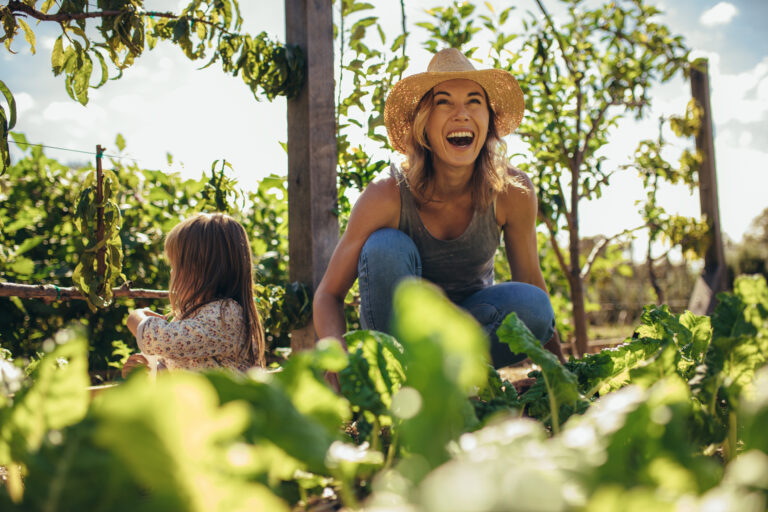Vrouw en kind werken samen in een duurzame moestuin met fruitbomen en groenten