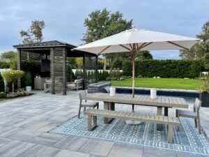 Grote parasol boven een lange tuintafel op een ruim terras