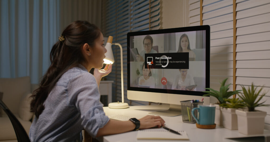 Vrouw werkt thuis achter een computer terwijl een videogesprek hapert door een slechte internetverbinding.