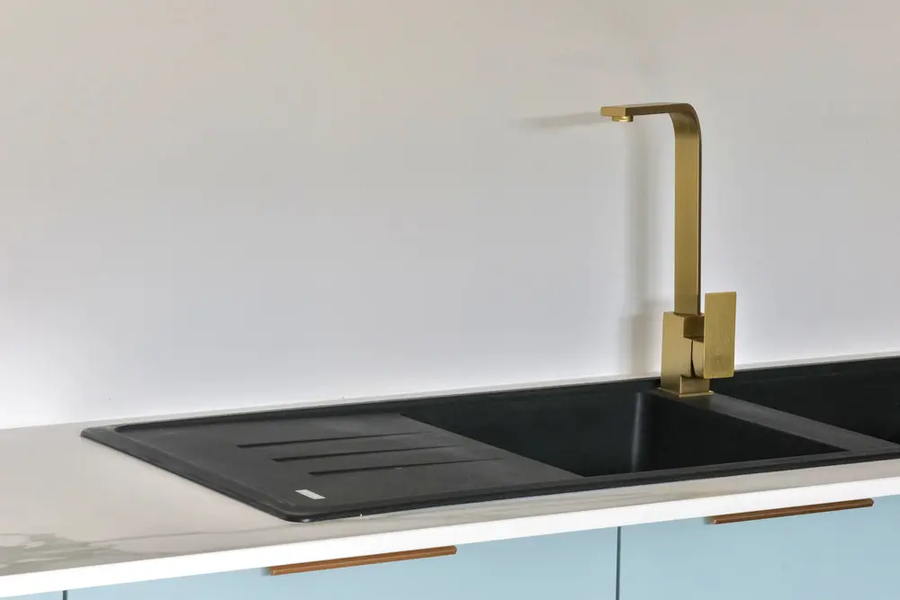 Messing keukenkraan boven zwarte spoelbak